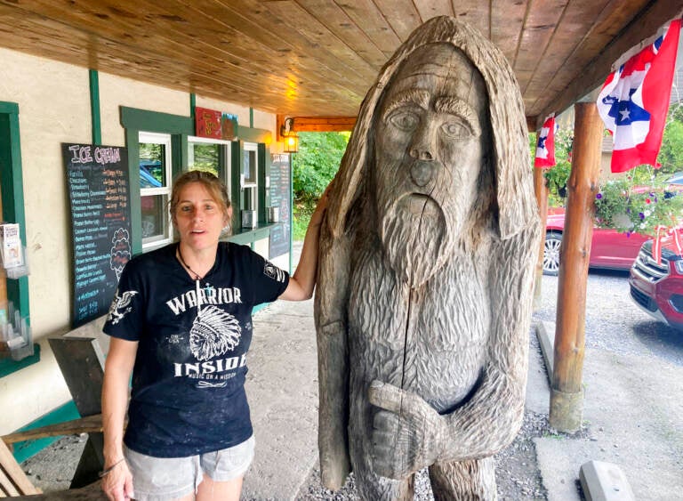 A woman stands next to a statue outside of a building.