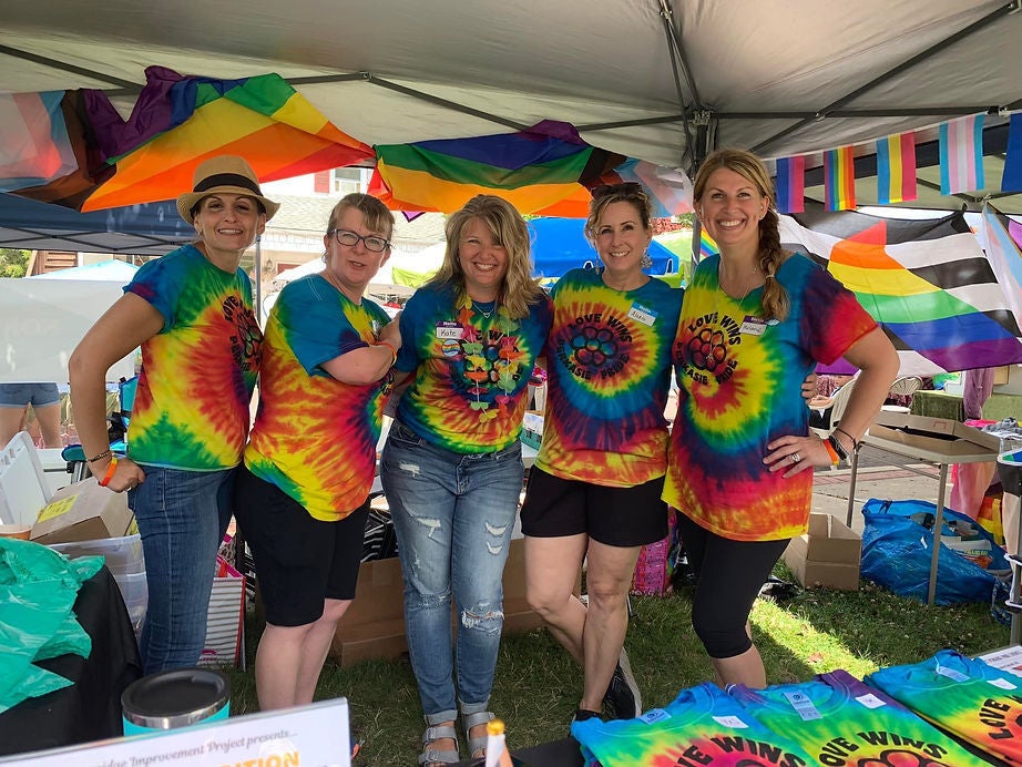 A group of people wearing tie-dye rainbow shirts pose for a photo.