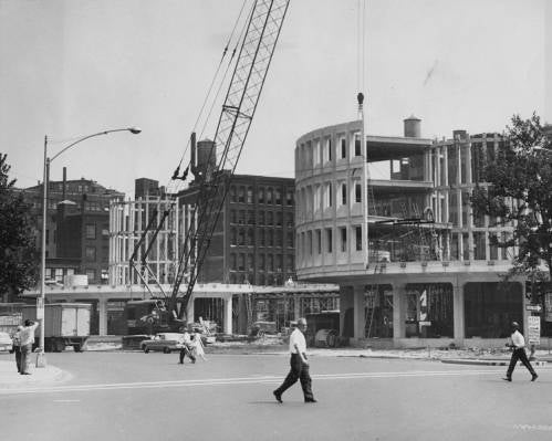 A black-and-white image of workers using a crane constructing the Roundhouse building.