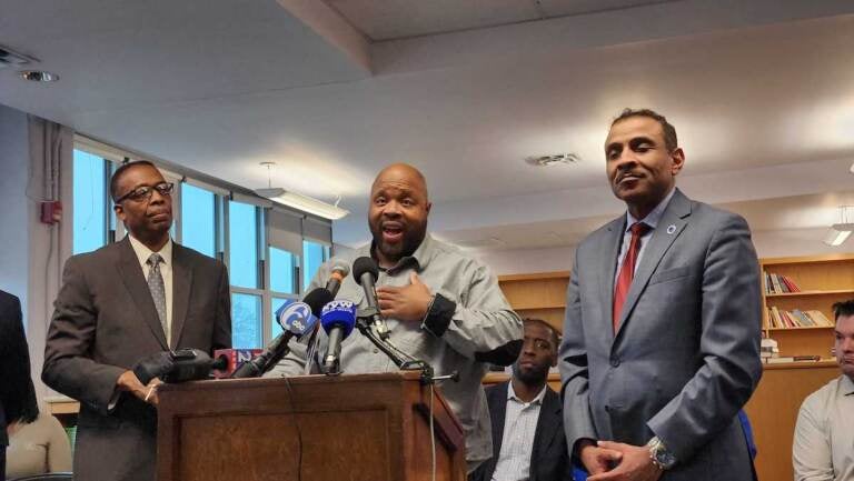 Three people speak at a podium.