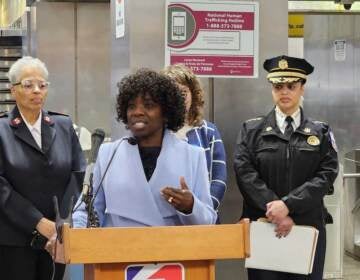 A person speaks at a podium in a SEPTA subway station.