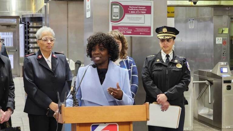 A person speaks at a podium in a SEPTA subway station.