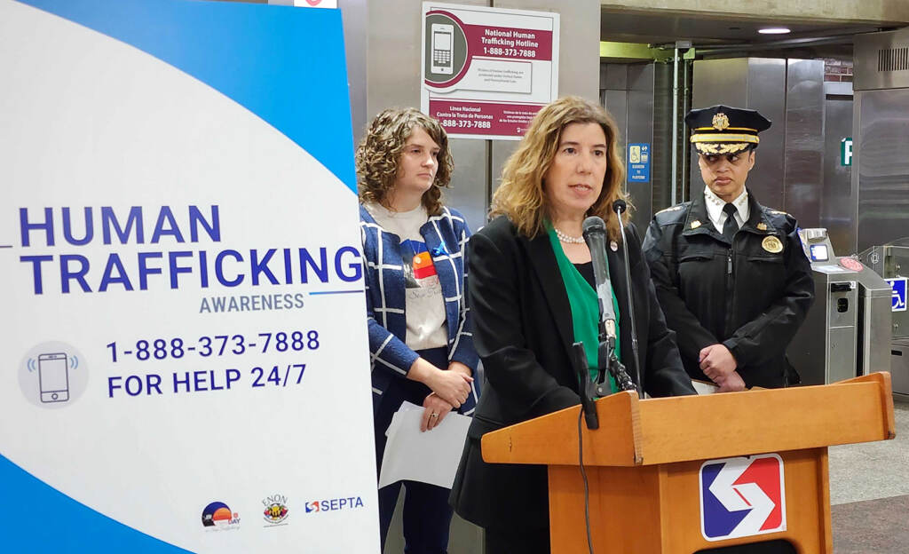 Leslie Richards speaks at a podium next to a sign that reads "Human Trafficking."