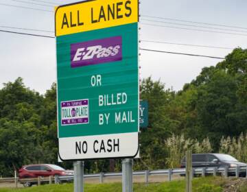 A sign reads E-ZPass. The highway is visible in the background.