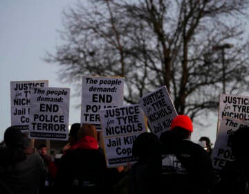 People hold up signs protesting the police killing of Tyre Nichols.