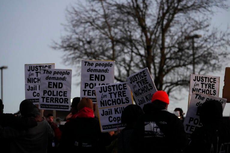 People hold up signs protesting the police killing of Tyre Nichols.