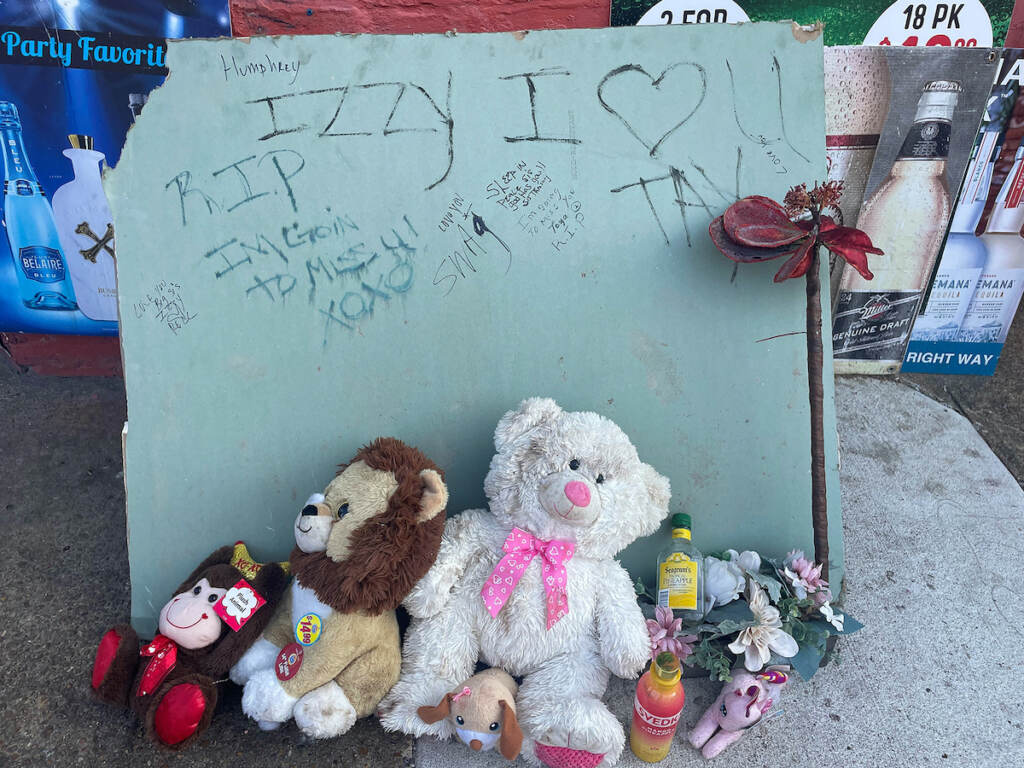 Several teddy bears are placed in front of a handwritten sign.