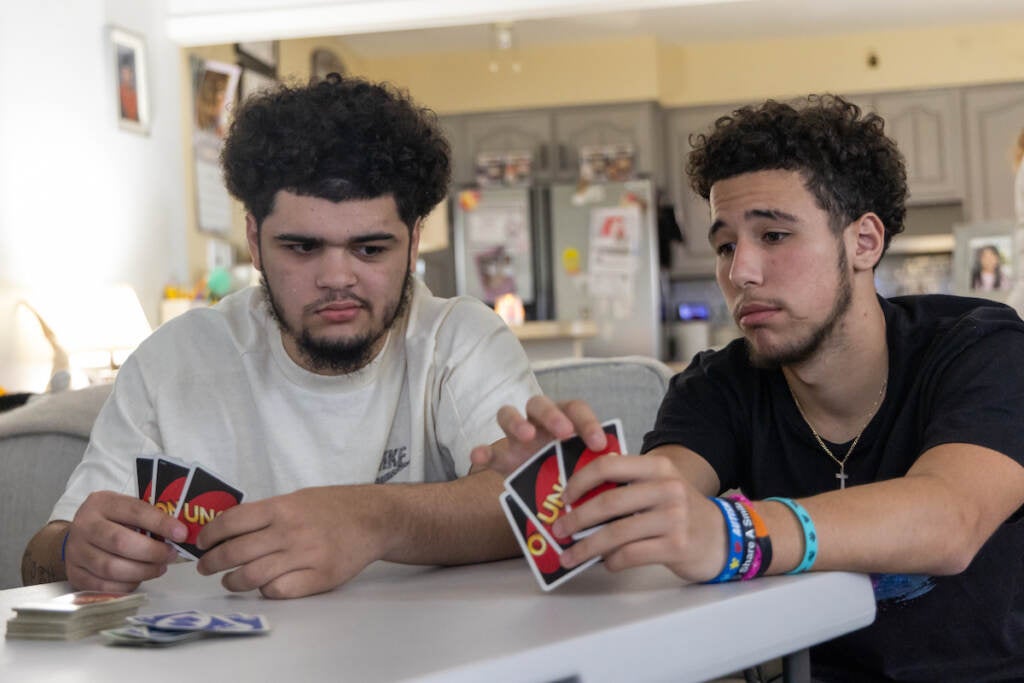 Two friends sit next to each other, playing Uno.