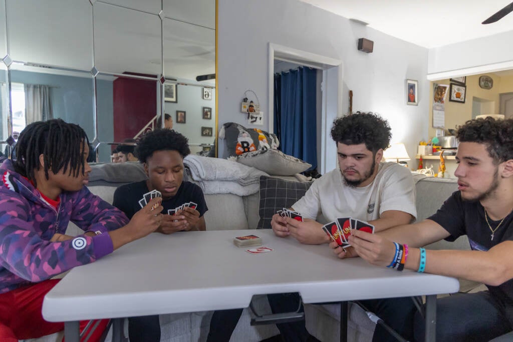 A group of teens sit around a table, playing Uno.