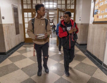 Synceir Thorton (right) and Taahzje Ellis (left), students at Dobbins Technical High School, walk together in the hall after school. (Kimberly Paynter/WHYY)