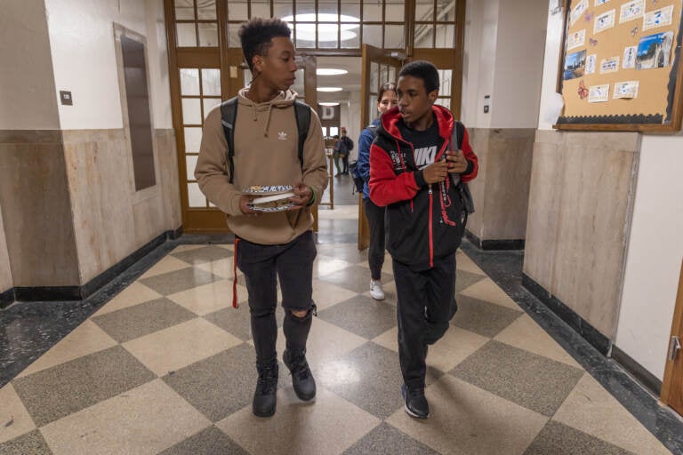 Synceir Thorton (right) and Taahzje Ellis (left), students at Dobbins Technical High School, walk together in the hall after school. (Kimberly Paynter/WHYY)
