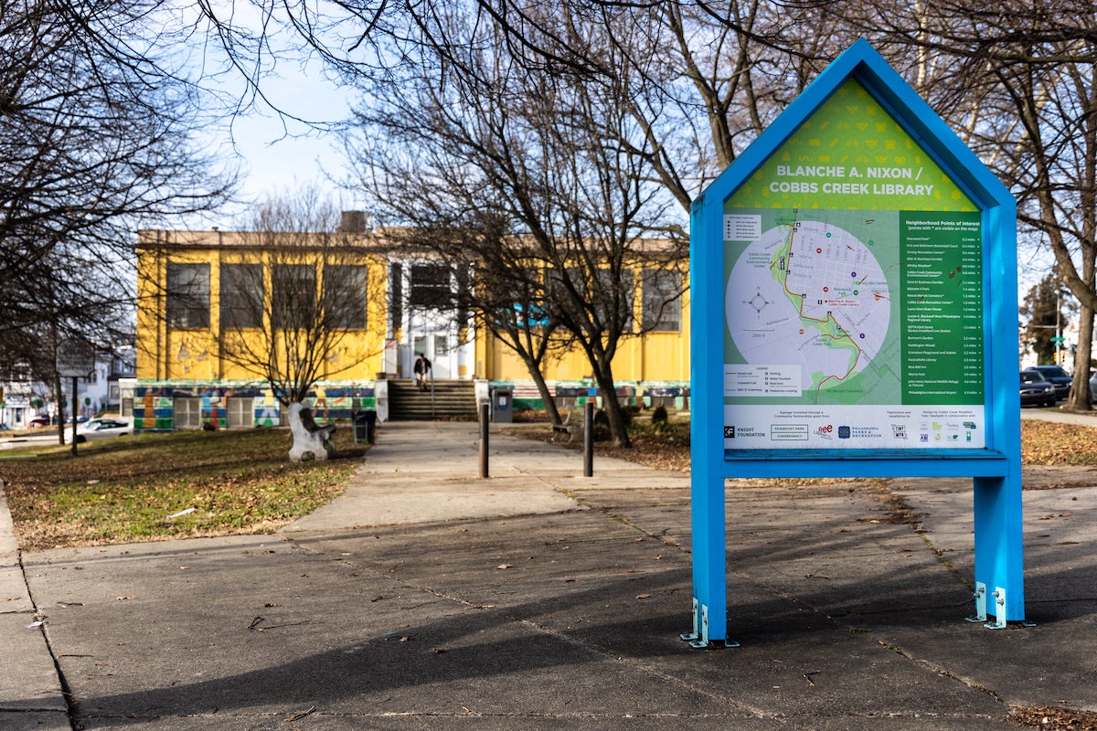 A map is visible in the foreground. A building and trees are in the background.