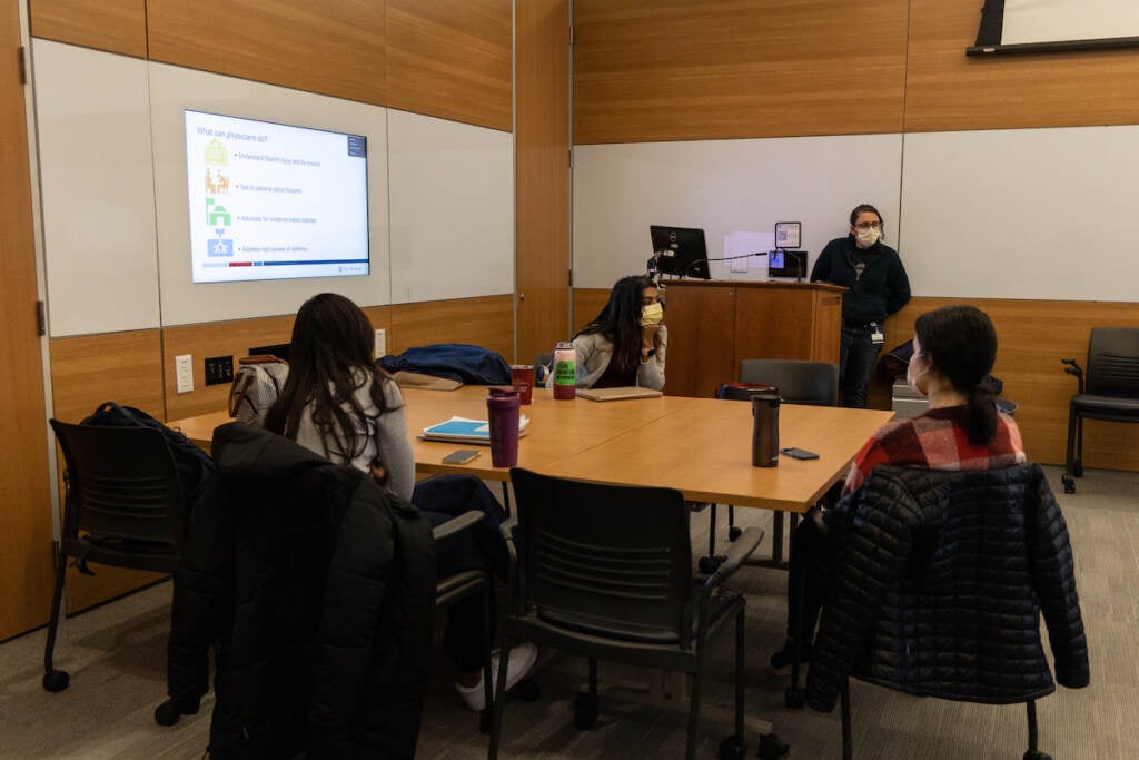 Students seated at a table look at a presentation.