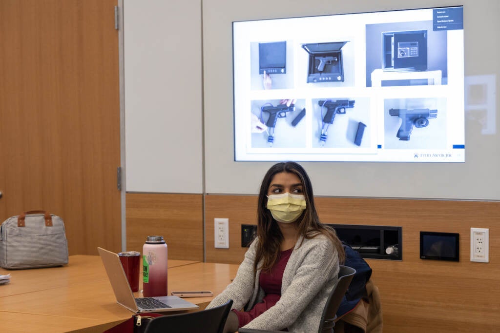 A student sits at a table with her laptop open.