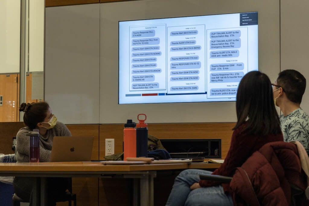 Students at a table look at a presentation.