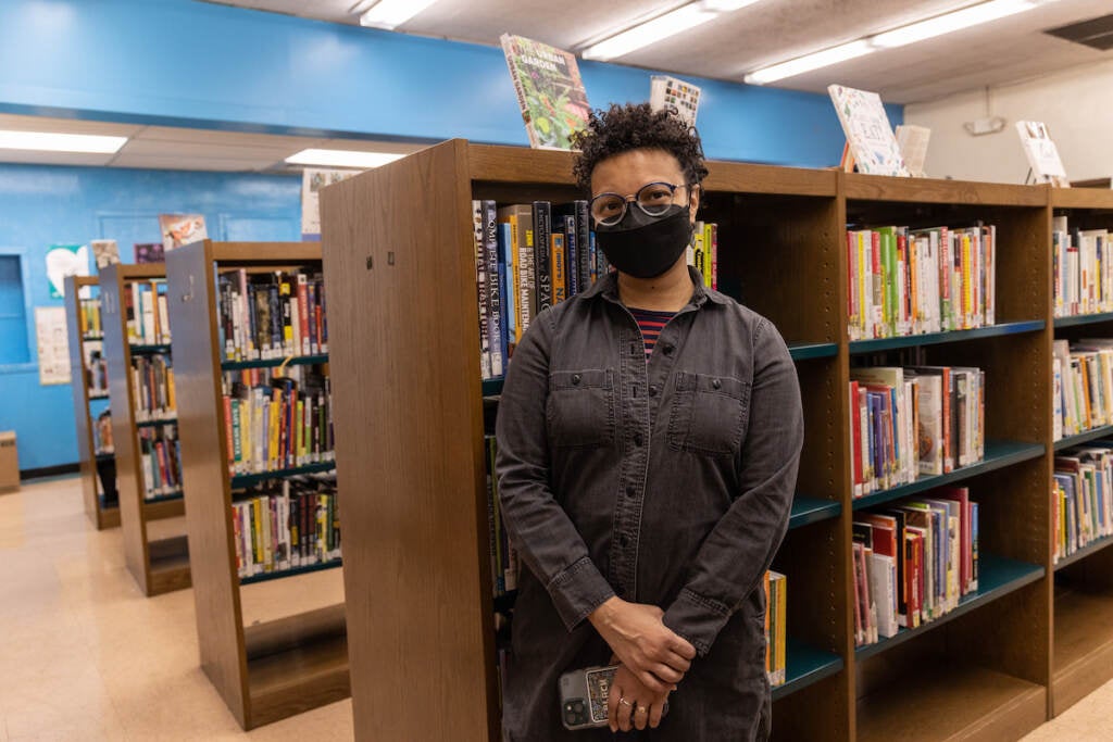 Jamie Bowers poses for a photo, in front of rows of bookshelves.