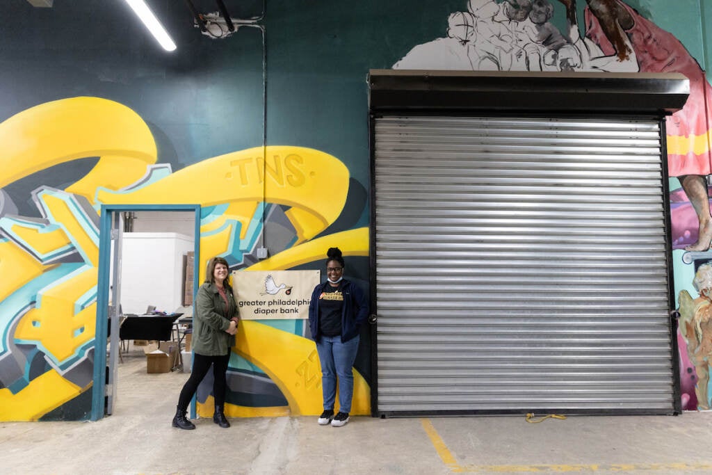 Two people pose for a photo inside of a large warehouse.