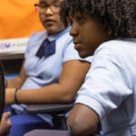 Donny looks off to the side as he sits in a chair in a classroom.