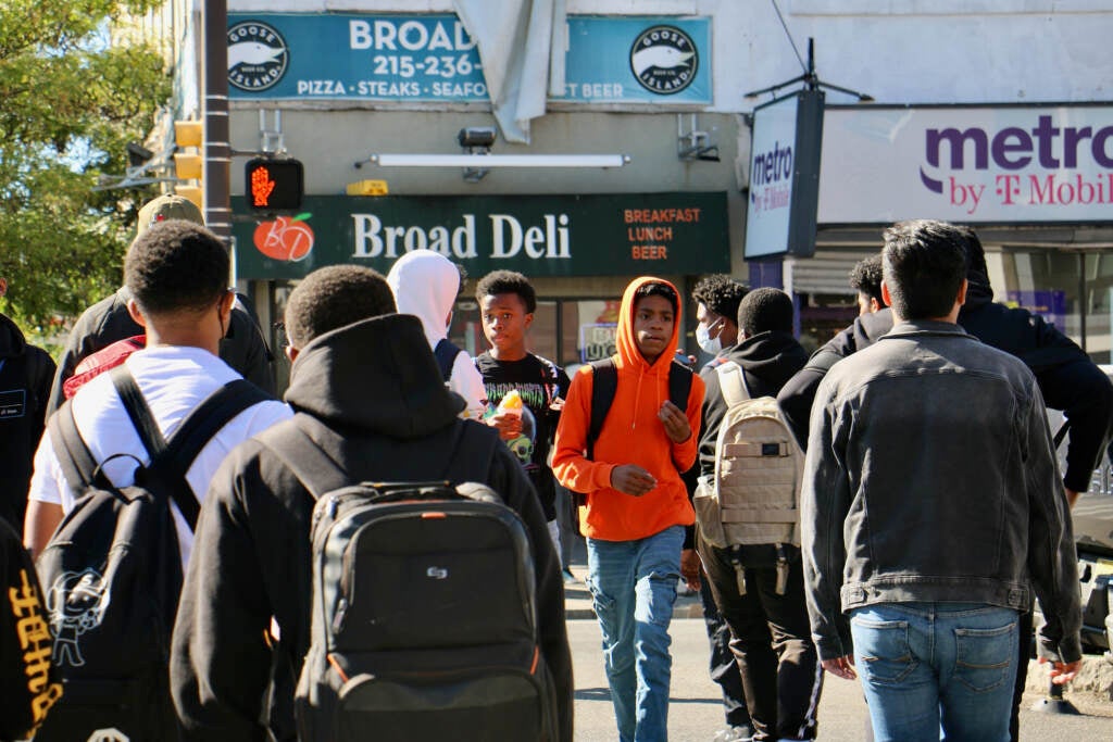 A crowd of people walk on the sidewalk.