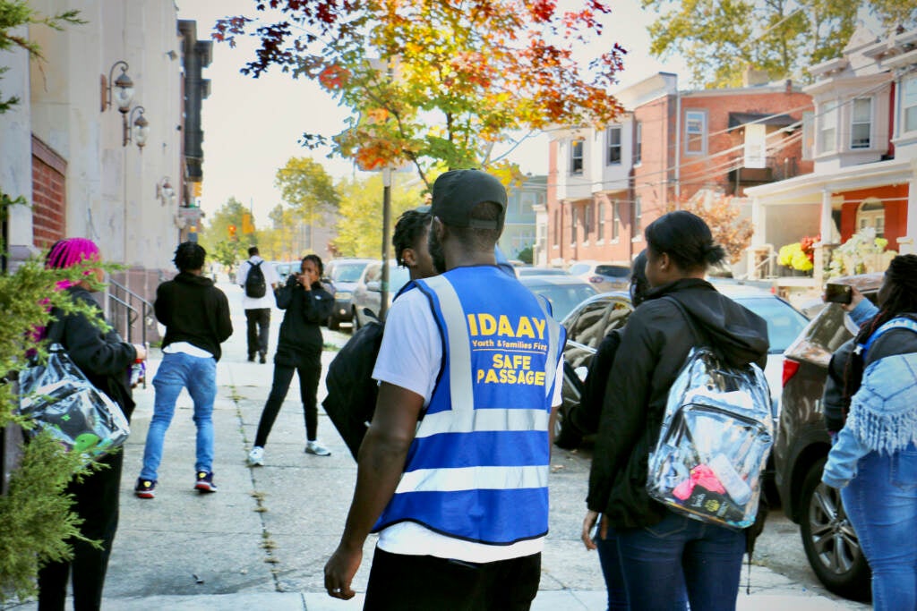 Malik Smith, seen from behind wearing a safety vest, walks with a group of students.