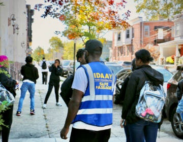 Malik Smith, seen from behind wearing a safety vest, walks with a group of students.