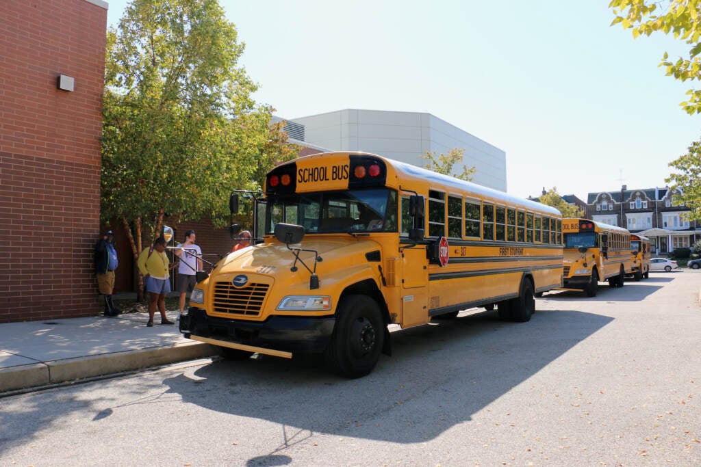 A view of a school bus is outside of a school building.