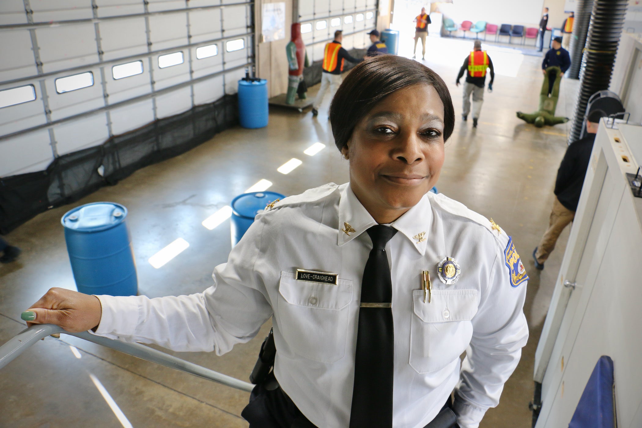 Altovise Love-Craighead smiles, paused on a staircase. Below her is a large space where police recruits are training.