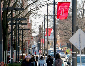 People walk by signs emblazoned with Temple's logo.