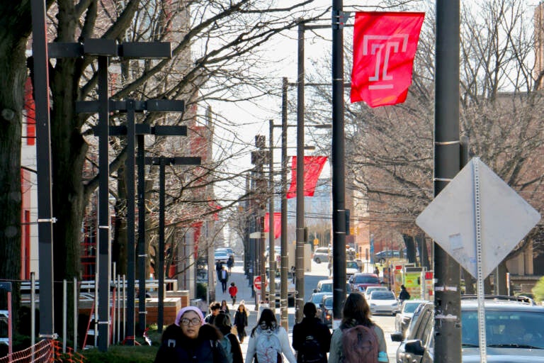 People walk by signs emblazoned with Temple's logo.