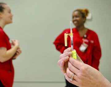 A Camden County health department employee prepares a COVID-19 booster shot while students from the Rutgers-Camden School of Nursing wait to administer vaccines during a clinic in the basement of the United Methodist Church in Haddon Heights.