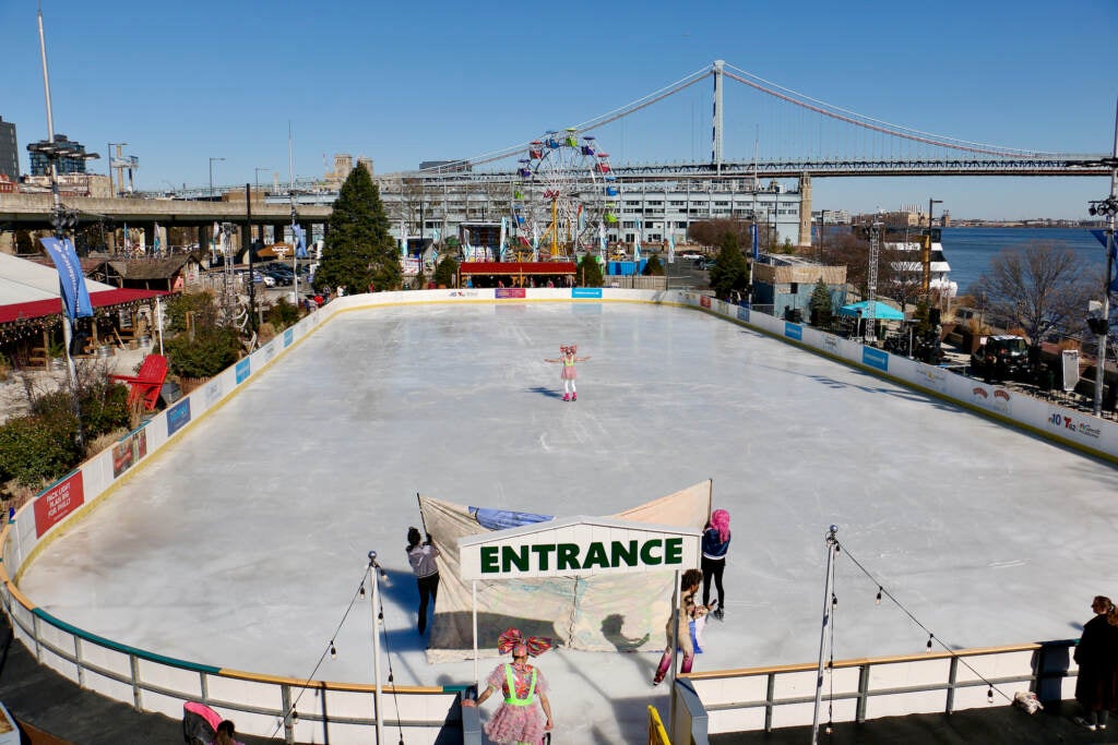 Skaters are visible on an ice skating rink from above.