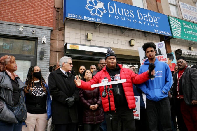 Frontline Dads CEO Rueben Jones stands in front of a coalition of anti-gun violence activists, religions and civic groups to demand $100 million from the city to support their work. (Emma Lee/WHYY)