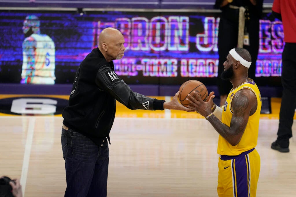 Kareem Abdul-Jabbar (left) hands the ball to Los Angeles Lakers forward LeBron James after passing Abdul-Jabbar to become the NBA's all-time leading scorer during the second half of an NBA basketball game against the Oklahoma City Thunder