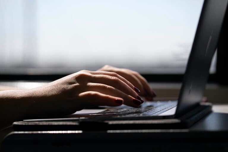 A woman types on a laptop while on a train in New Jersey