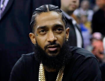 Rapper Nipsey Hussle attends an NBA basketball game between the Golden State Warriors and the Milwaukee Bucks in Oakland, Calif.