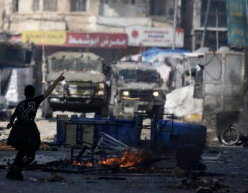 A Palestinian gestures to Israeli military vehicles during clashes in the West Bank city of Nablus