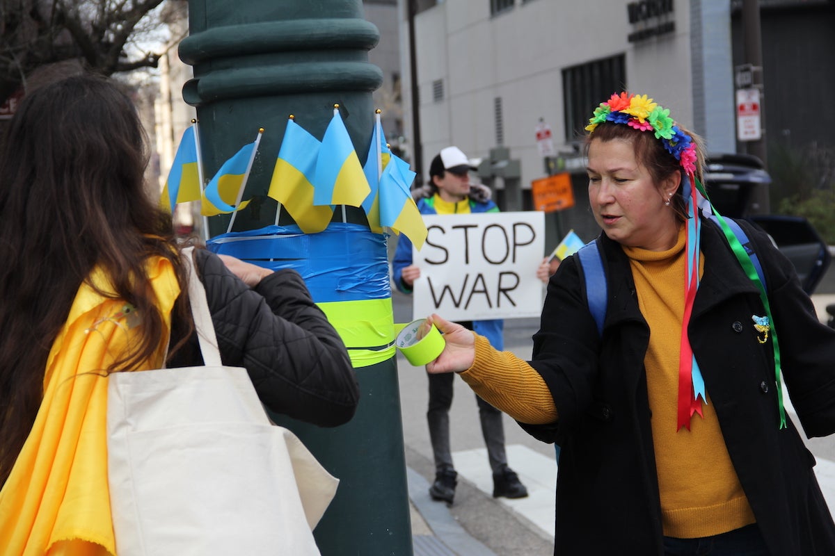 Rada Dubashinsky tapes Ukraine flags to a street pole