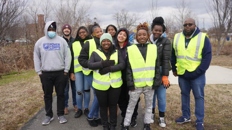 A group of people in yellow reflective vests pose for a photo outdoors.