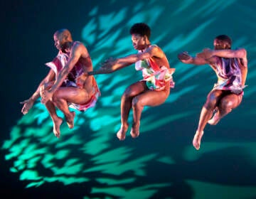 Dancers leap in the air against a colorful backdrop.