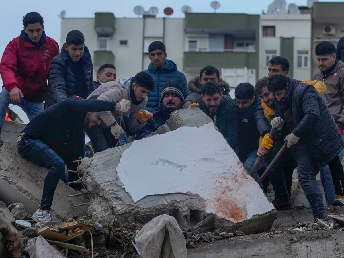 Men search for people among the debris in a destroyed building in Adana, Turkey, Monday.