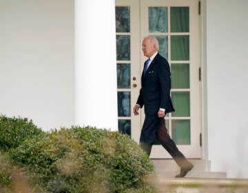 Biden walks in an outdoor corridor at the White House.