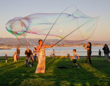 A person makes a giant soap bubble.