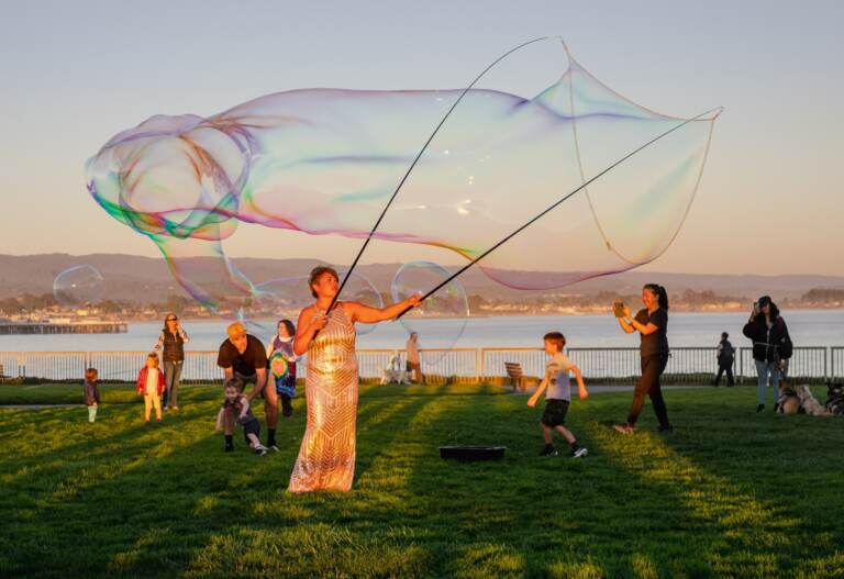A person makes a giant soap bubble.