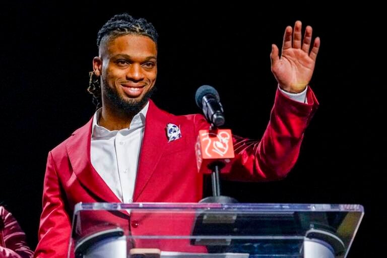 Damar Hamlin waves at a podium.