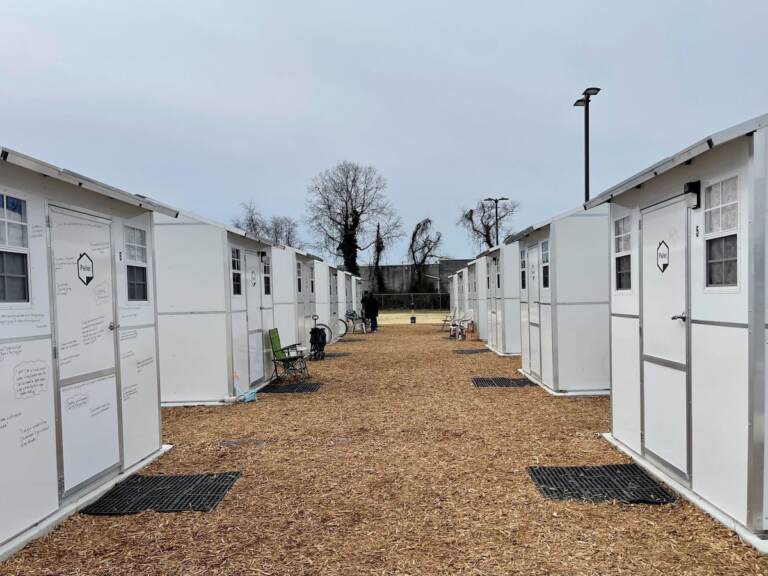 A walkway stretches into the distance, lined by rows of small white homes on either side.