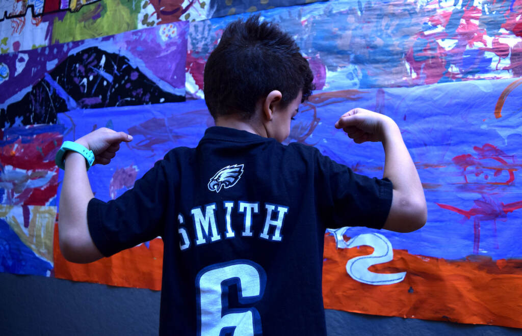 A kid poses, showing off his Eagles jersey.