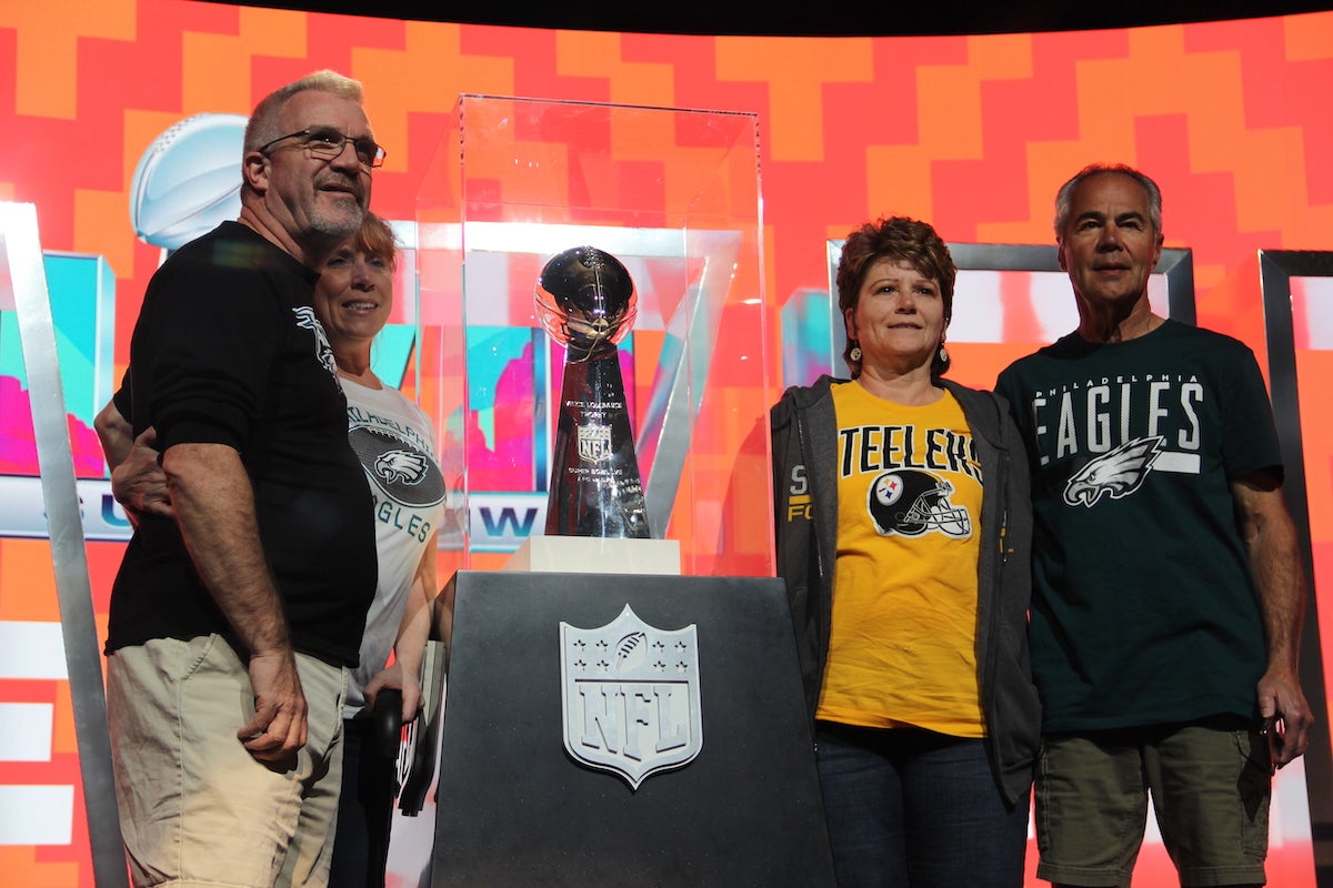 People pose onstage with the Lombardi trophy.