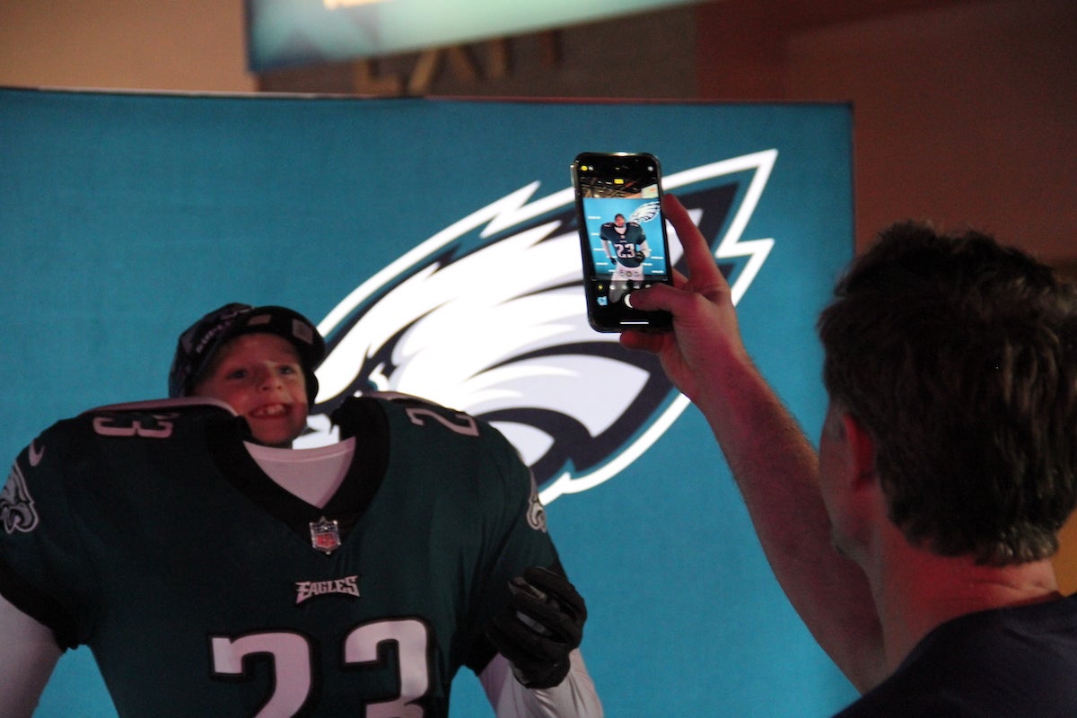 A person takes a photo of a kid posing with an Eagles uniform.
