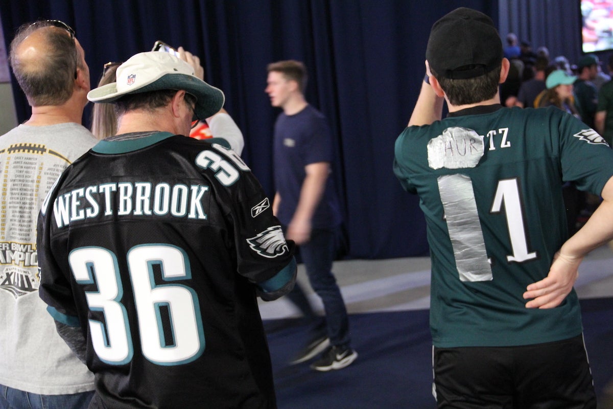 A group of Eagles fans are wearing different Eagles jerseys.