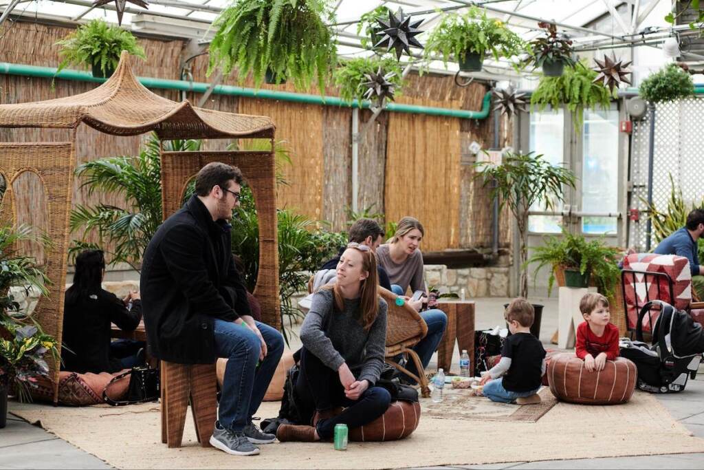 People sit down and hang out in a greenhouse.